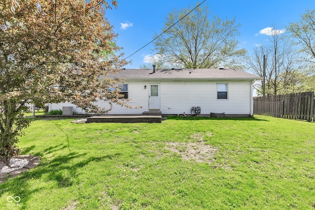 rear view of house featuring fence and a lawn