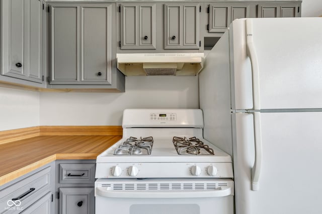 kitchen featuring white appliances, under cabinet range hood, gray cabinets, and light countertops