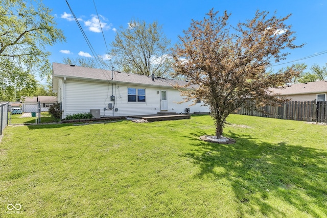 rear view of property featuring a fenced backyard, central air condition unit, and a yard