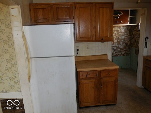 923 Woodview Blvd, Fort Wayne, IN 46806 - kitchen featuring light countertops, brown cabinets, wallpapered walls, and freestanding refrigerator