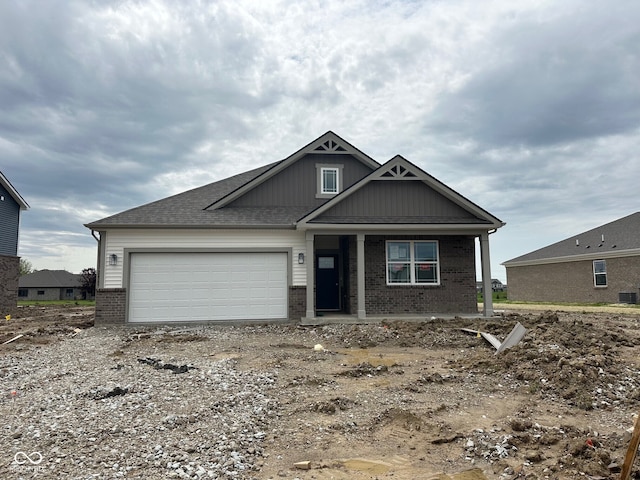craftsman-style house with brick siding, an attached garage, central AC, and dirt driveway