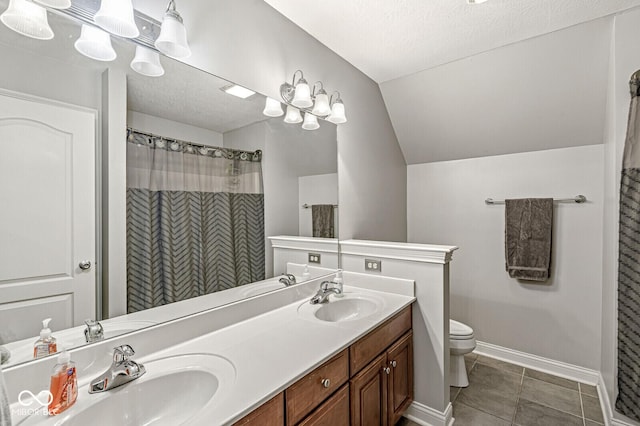 full bath with toilet, double vanity, a sink, and lofted ceiling