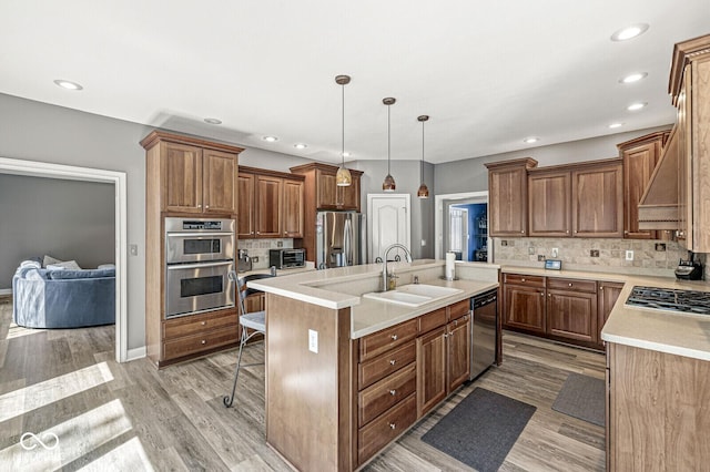 kitchen with a kitchen breakfast bar, tasteful backsplash, a sink, appliances with stainless steel finishes, and an island with sink