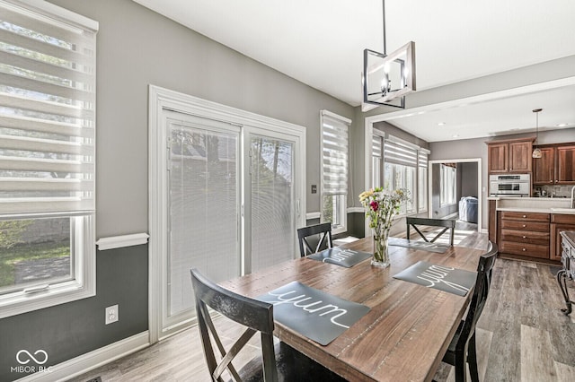 dining room with baseboards, light wood-type flooring, and a notable chandelier