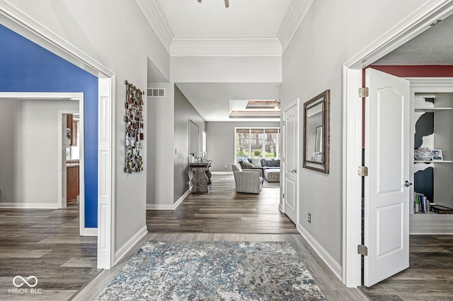 foyer entrance featuring baseboards, visible vents, wood finished floors, and crown molding