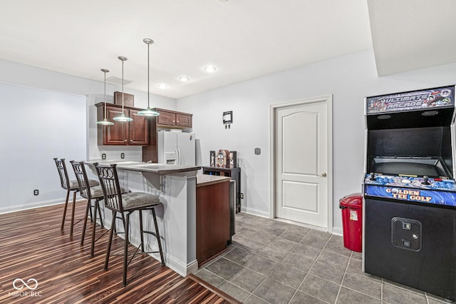kitchen with recessed lighting, white refrigerator with ice dispenser, a breakfast bar, decorative light fixtures, and a peninsula