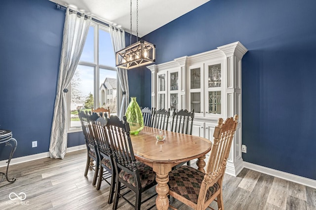 dining area featuring light wood-style floors, a notable chandelier, and baseboards