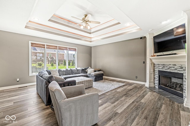 living area with visible vents, crown molding, a tray ceiling, and a ceiling fan