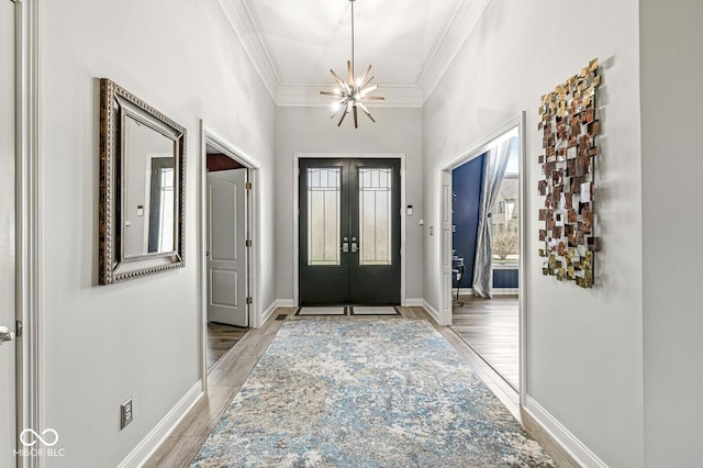 foyer entrance with crown molding, baseboards, an inviting chandelier, light wood finished floors, and french doors