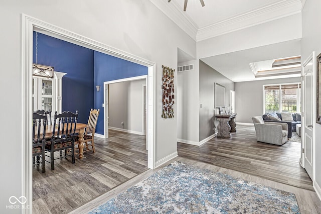 hall with wood finished floors, ornamental molding, and baseboards