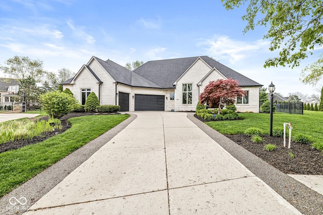view of front facade featuring a front lawn, driveway, brick siding, an attached garage, and fence