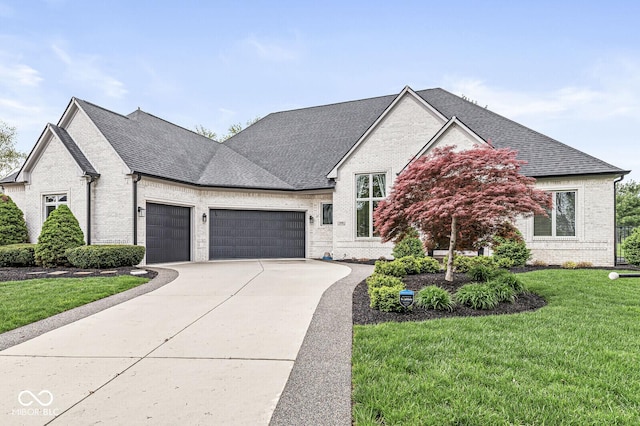 view of front facade with concrete driveway, a shingled roof, brick siding, a front lawn, and a garage
