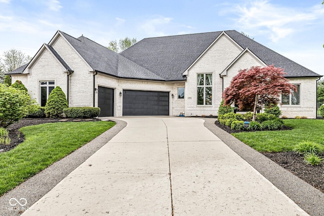 view of front facade with a front yard, brick siding, roof with shingles, concrete driveway, and an attached garage