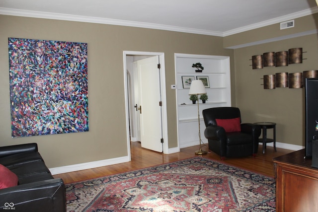 sitting room featuring baseboards, visible vents, crown molding, and wood finished floors