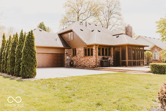 6712 Forrest Commons Blvd, Indianapolis, IN 46227 - rear view of house with concrete driveway, a chimney, an attached garage, a yard, and a sunroom