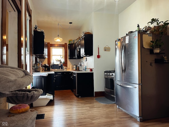 310 E Central Ave, Greensburg, IN 47240 - kitchen featuring stainless steel appliances, light countertops, light wood-style floors, dark cabinetry, and hanging light fixtures
