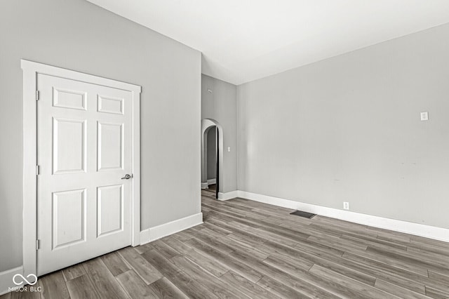 2006 Lexington Ave, Indianapolis, IN 46203 - empty room with arched walkways, wood finished floors, baseboards, and visible vents