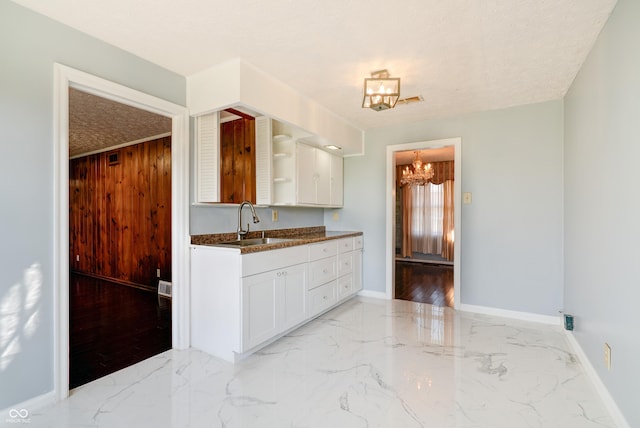 6047 W 56th St, Indianapolis, IN 46254 - kitchen with white cabinetry, open shelves, marble finish floor, a sink, and a notable chandelier