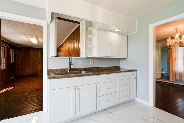 6047 W 56th St, Indianapolis, IN 46254 - kitchen with a textured ceiling, marble finish floor, white cabinetry, a sink, and an inviting chandelier