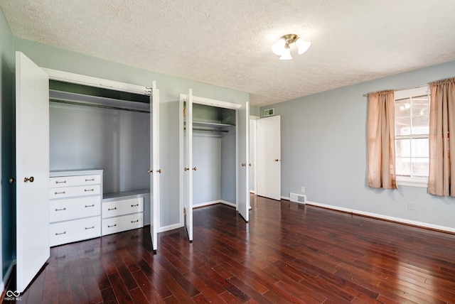 6047 W 56th St, Indianapolis, IN 46254 - unfurnished bedroom featuring two closets, visible vents, wood finished floors, and a textured ceiling