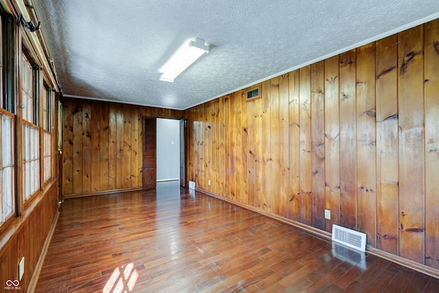 6047 W 56th St, Indianapolis, IN 46254 - empty room featuring baseboards, a textured ceiling, wooden walls, visible vents, and wood finished floors