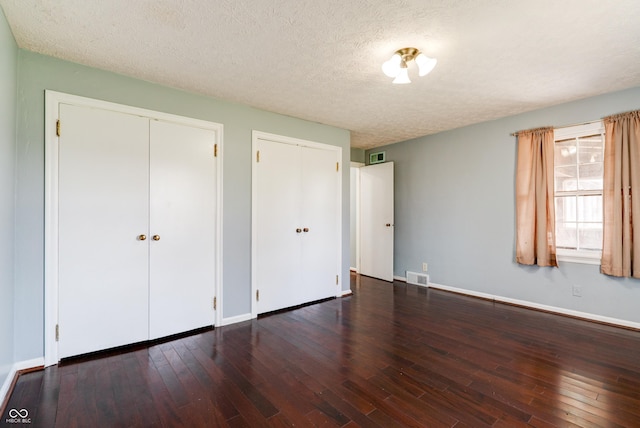 6047 W 56th St, Indianapolis, IN 46254 - unfurnished bedroom featuring baseboards, multiple closets, a textured ceiling, hardwood / wood-style flooring, and visible vents