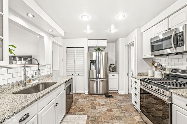 5028 Graceland Ave, Indianapolis, IN 46208 - kitchen with white cabinetry, appliances with stainless steel finishes, a sink, and tasteful backsplash