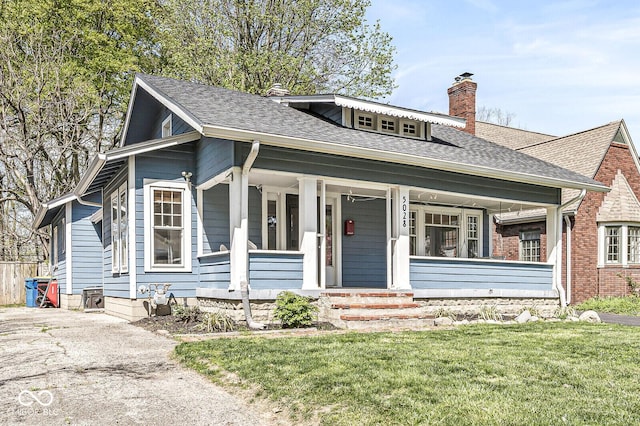 5028 Graceland Ave, Indianapolis, IN 46208 - bungalow-style house with a shingled roof, a front yard, a chimney, and covered porch