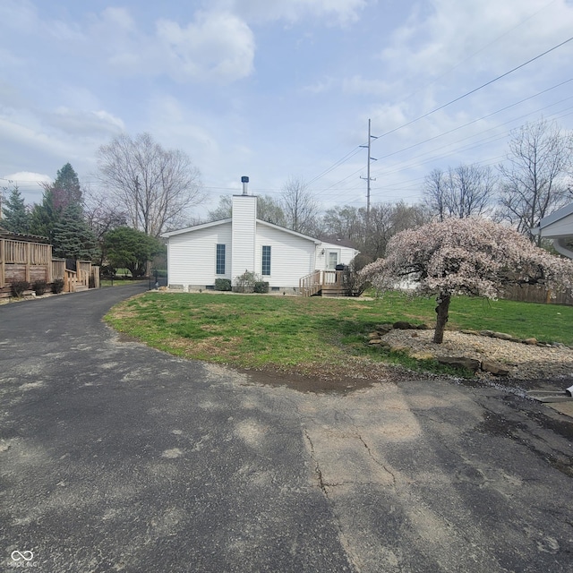1024 Foltz St, Indianapolis, IN 46241 - view of home's exterior featuring aphalt driveway, a yard, and a chimney
