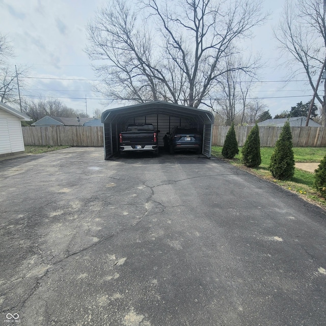 1024 Foltz St, Indianapolis, IN 46241 - view of vehicle parking featuring driveway, fence, and a carport