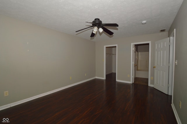 5406 Shamus Dr, Indianapolis, IN 46235 - unfurnished bedroom featuring dark wood-style flooring, baseboards, a walk in closet, ceiling fan, and a textured ceiling