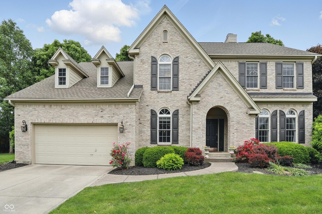 11974 Volcanic Rock Dr, Fishers, IN 46037 - view of front of property with roof with shingles, driveway, a garage, a chimney, and a front lawn
