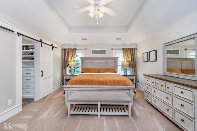 2353 Woodcreek Crossing Blvd, Avon, IN 46123 - bedroom with a barn door, a tray ceiling, light colored carpet, and a ceiling fan