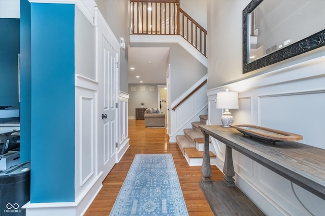 2353 Woodcreek Crossing Blvd, Avon, IN 46123 - entryway featuring stairway, wood finished floors, a decorative wall, a high ceiling, and a wainscoted wall