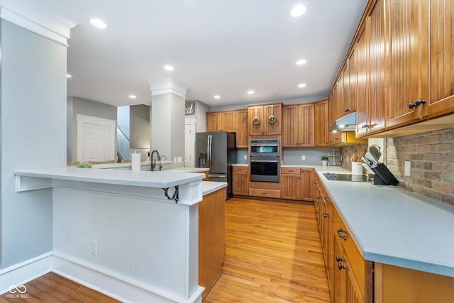 2353 Woodcreek Crossing Blvd, Avon, IN 46123 - kitchen with stainless steel appliances, under cabinet range hood, light wood-style flooring, brown cabinetry, and recessed lighting