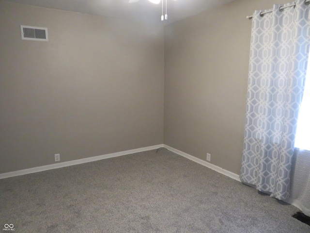 carpeted spare room with baseboards, visible vents, and ceiling fan