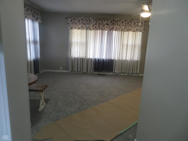 interior space with baseboards, ceiling fan, and carpet