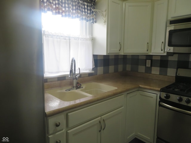 kitchen with light countertops, a sink, white cabinetry, tasteful backsplash, and stainless steel appliances