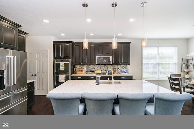 kitchen featuring appliances with stainless steel finishes, dark wood-style floors, a sink, and a kitchen bar