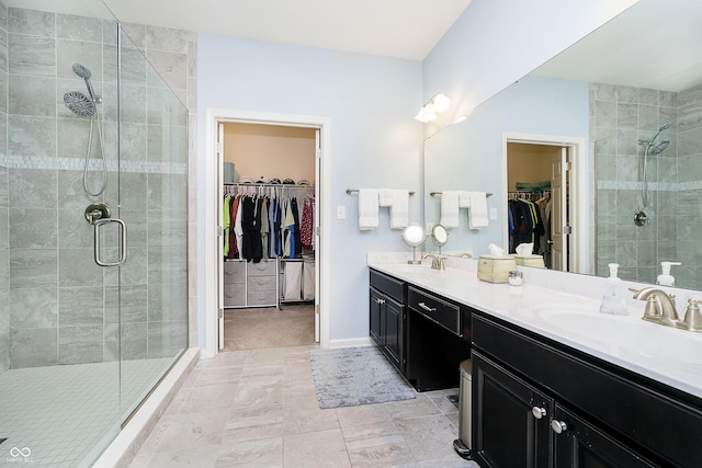 bathroom featuring double vanity, a sink, a walk in closet, and a stall shower