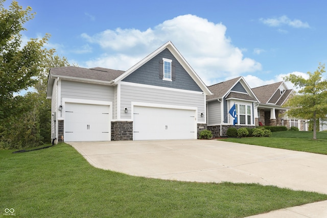 craftsman-style home with a front yard, driveway, stone siding, and a garage