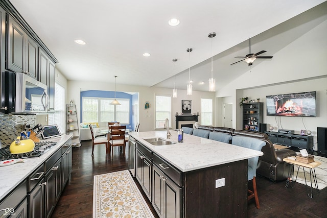 kitchen featuring a sink, open floor plan, a breakfast bar area, a ceiling fan, and appliances with stainless steel finishes