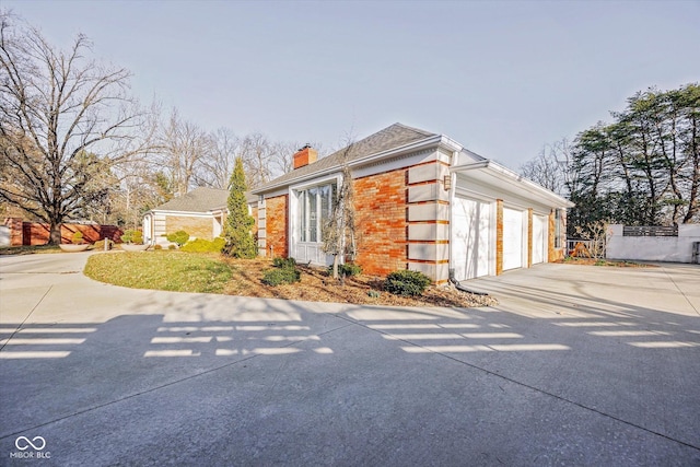 1227 S Pickwick Pt, Bloomington, IN 47401 - view of front of house featuring brick siding, concrete driveway, a garage, and a chimney