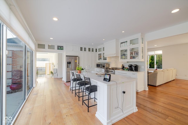 1227 S Pickwick Pt, Bloomington, IN 47401 - kitchen with light wood-type flooring, a breakfast bar area, decorative backsplash, and appliances with stainless steel finishes