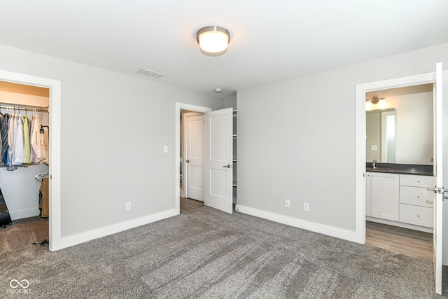 unfurnished bedroom featuring baseboards, visible vents, a walk in closet, and carpet