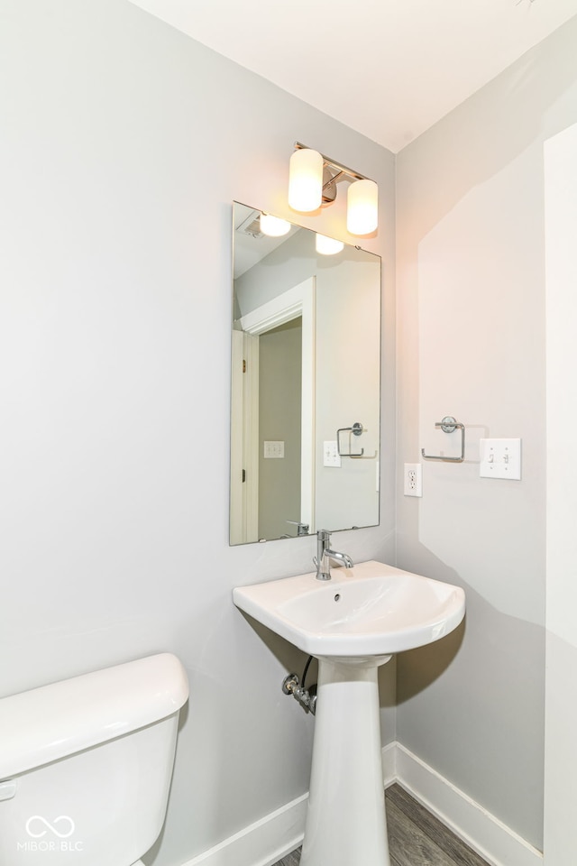half bath featuring toilet, baseboards, and wood finished floors