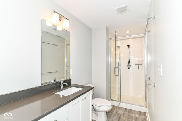 full bathroom with visible vents, vanity, wood finished floors, toilet, and a stall shower