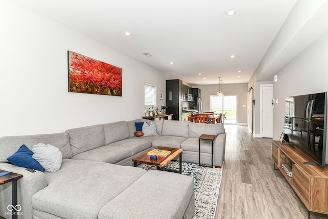 living room with recessed lighting, baseboards, and light wood-style floors