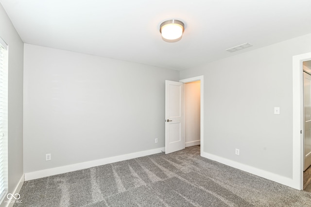spare room with carpet floors, baseboards, and visible vents
