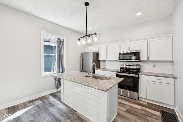 422 N Oxford St, Indianapolis, IN 46201 - kitchen featuring stainless steel appliances, a sink, backsplash, a center island with sink, and white cabinets